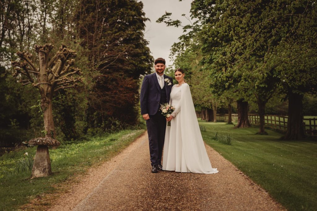 Bride and groom on tree-lined path at wedding.