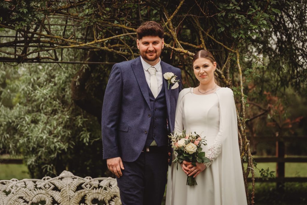 Couple poses together during outdoor wedding ceremony.