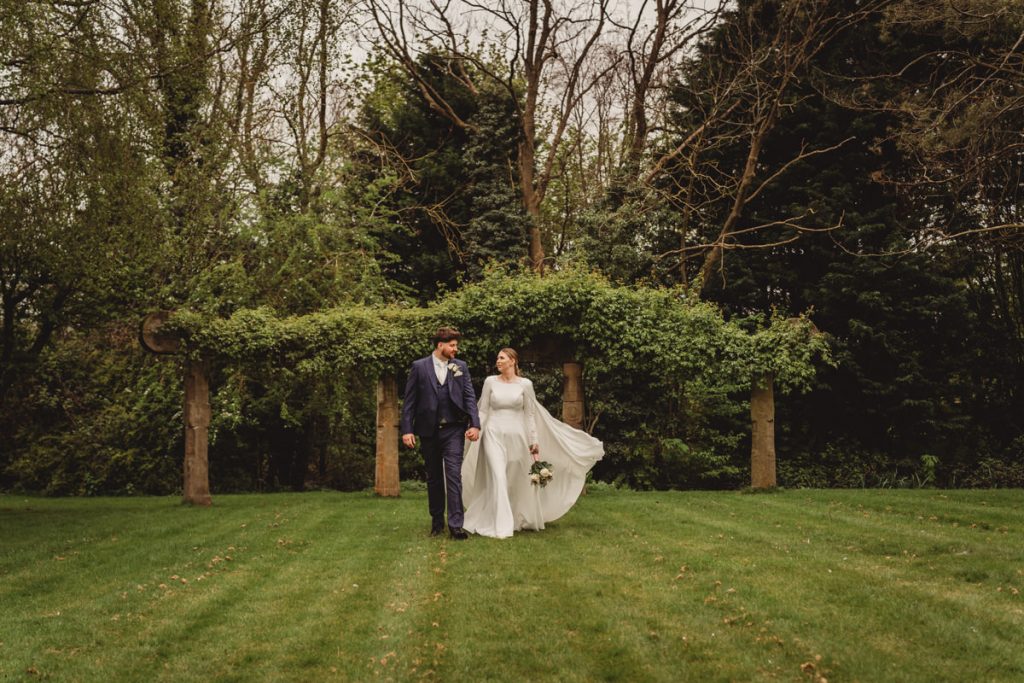 Couple walking in a garden on wedding day.