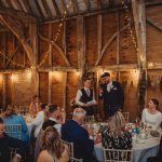 Wedding speech in rustic barn setting, guests listening.