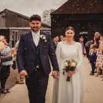 Bride and groom walking through confetti celebration.