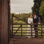 Bride and groom at rustic wooden gate outdoors.