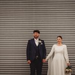 Wedding couple standing in front of metal shutter.