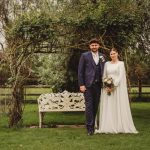 Wedding couple in garden under wooden arch