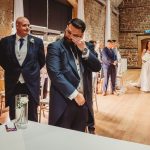 Emotional groom watches bride walk down the aisle.