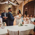 Bride and groom exchange vows in rustic venue.