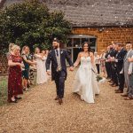 Bride and groom walking through confetti, smiling guests.