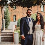 Couple posing outdoors in wedding attire.