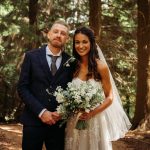 Bride and groom smiling in forest setting.