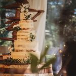 Rustic wedding cake with white flowers and greenery.