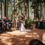 Bride and groom kissing at forest wedding ceremony.