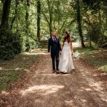 Wedding couple walking through a forest path