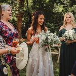 Bride with bridesmaids at outdoor wedding gathering.