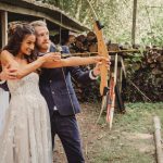 Bride and groom practicing archery outdoors