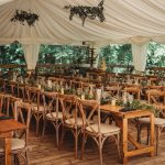 Rustic wedding reception with wooden chairs and tables.