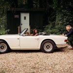 Person pushing vintage white convertible car