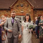 Bride and groom exiting wedding ceremony, joyful moment.