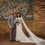 Wedding couple in front of mosaic wall mural.