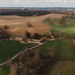 Aerial view of English countryside fields and buildings.