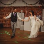 Bride and groom dancing joyfully at wedding reception.