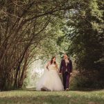 Couple walking in forest on wedding day.