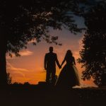 Silhouetted couple holding hands at sunset.