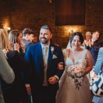 Bride and groom walk down the aisle, smiling.