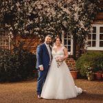 Bride and groom smiling in garden setting.