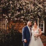 Bride and groom smiling in garden setting.