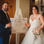 Bride and groom next to wedding sign.