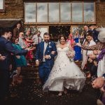 Happy couple exits wedding ceremony amid confetti celebration.