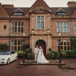 Bride and groom outside historic English manor house.