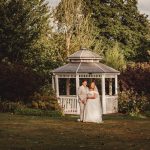 Bride and groom under a garden gazebo