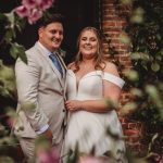 Smiling couple on wedding day near flowers.