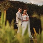 Bride and groom in garden setting, smiling happily.