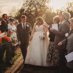 Bride and groom walking through confetti shower outdoors.