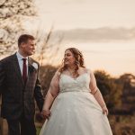 Bride and groom holding hands at sunset.