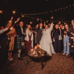 Group celebrating with sparklers around fire pit