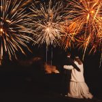 Couple watching fireworks display at night wedding celebration.