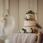 Three-tier naked wedding cake with flowers.