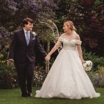 Bride and groom holding hands in garden.