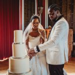 Bride and groom cutting tiered wedding cake.