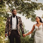 Bride and groom holding hands under tree.