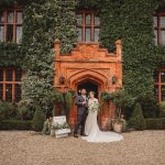 Bride and groom outside ivy-covered brick building.