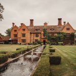 Historic manor house with garden and water feature.