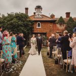 Bride and groom walk down outdoor wedding aisle