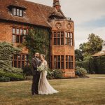 Couple poses in front of historic brick building.