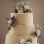 Three-tier wedding cake with floral decorations.