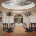 Elegant wedding hall with floral decorations and skylight.