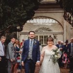 Newlyweds walking down aisle, surrounded by guests.